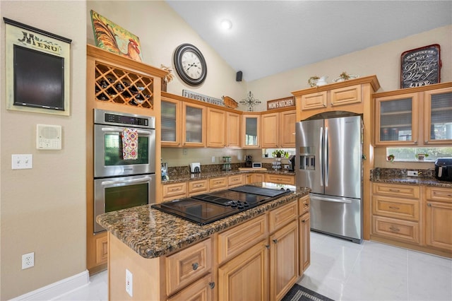 kitchen with stainless steel appliances, dark stone countertops, light tile patterned floors, a center island, and glass insert cabinets