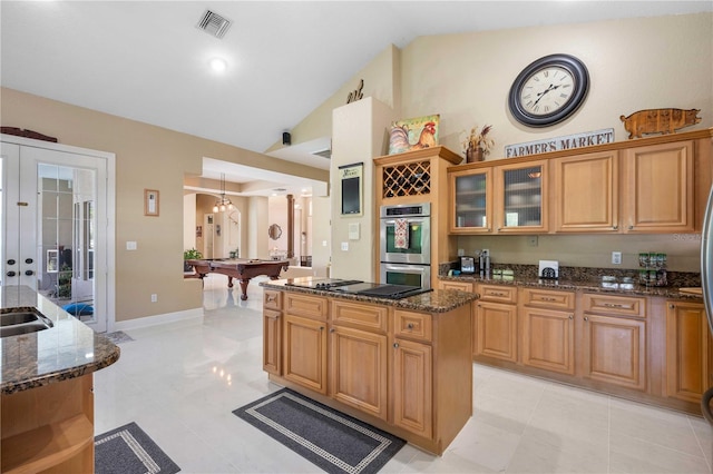 kitchen featuring double oven, black electric cooktop, billiards, a kitchen island, and dark stone counters