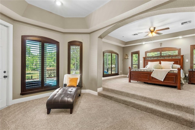 bedroom with light carpet, a tray ceiling, visible vents, and baseboards