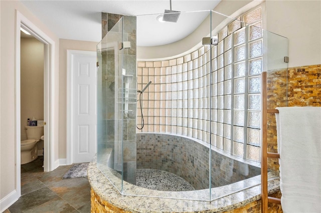 full bathroom with walk in shower, baseboards, and toilet
