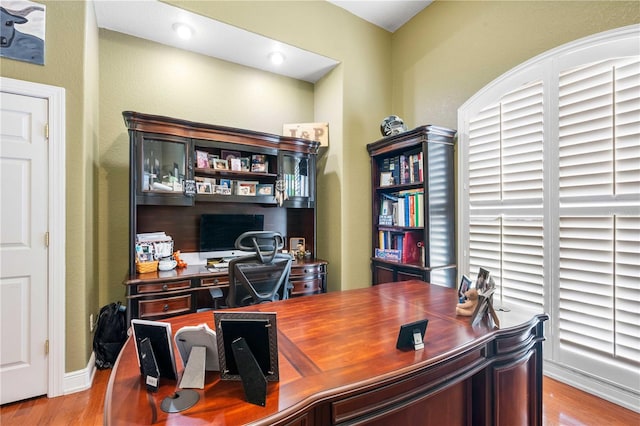 home office with baseboards and wood finished floors