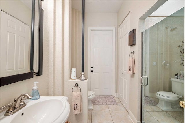 full bathroom featuring toilet, tile patterned flooring, a sink, and a stall shower