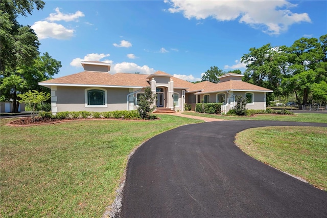 mediterranean / spanish home featuring stucco siding, a front lawn, and driveway