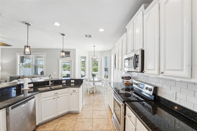7207 Forest Mere Dr, Riverview, FL 33578 - kitchen featuring stainless steel appliances, a sink, decorative backsplash, white cabinetry, and pendant lighting