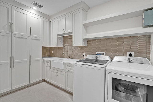 laundry area featuring visible vents, separate washer and dryer, cabinet space, and a sink