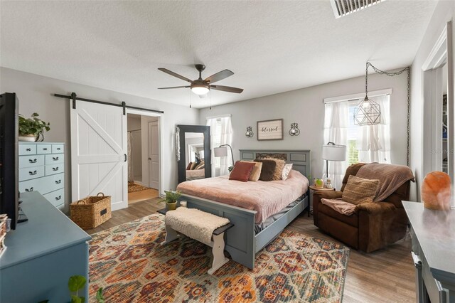 10101 Mangrove Well Rd, Ruskin, FL 33573 - bedroom with a textured ceiling, wood finished floors, visible vents, and a barn door
