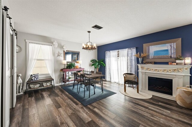 10101 Mangrove Well Rd, Ruskin, FL 33573 - dining space featuring a fireplace, a textured ceiling, visible vents, wood finished floors, and a notable chandelier
