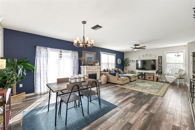 10101 Mangrove Well Rd, Ruskin, FL 33573 - dining area featuring dark wood-style flooring, a fireplace, a textured ceiling, visible vents, and ceiling fan with notable chandelier