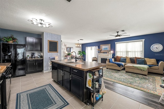 10101 Mangrove Well Rd, Ruskin, FL 33573 - kitchen featuring a sink, light tile patterned floors, dark cabinetry, ceiling fan with notable chandelier, and black appliances