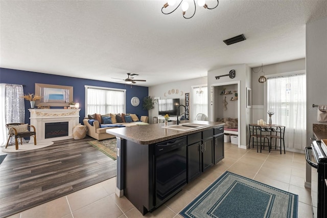 10101 Mangrove Well Rd, Ruskin, FL 33573 - kitchen with a sink, dark countertops, an island with sink, black appliances, and light tile patterned flooring