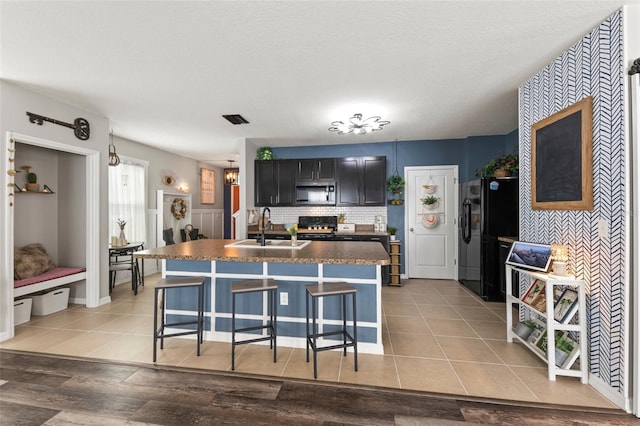 10101 Mangrove Well Rd, Ruskin, FL 33573 - kitchen with stainless steel microwave, black fridge, dark countertops, stove, and a sink