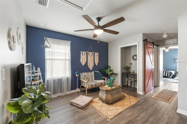 10101 Mangrove Well Rd, Ruskin, FL 33573 - living area with visible vents, baseboards, a barn door, a ceiling fan, and wood finished floors