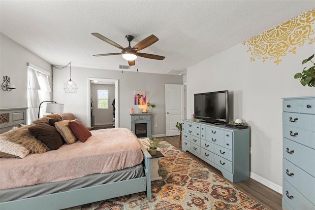 10101 Mangrove Well Rd, Ruskin, FL 33573 - bedroom with baseboards, a ceiling fan, a textured ceiling, a fireplace, and wood finished floors