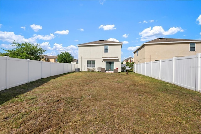 10101 Mangrove Well Rd, Ruskin, FL 33573 - rear view of house with central AC, a fenced backyard, a lawn, and stucco siding