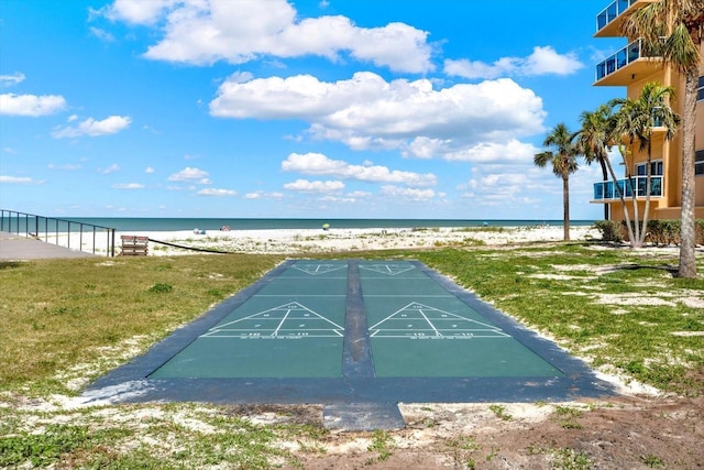 view of community featuring a water view, shuffleboard, a beach view, and a yard