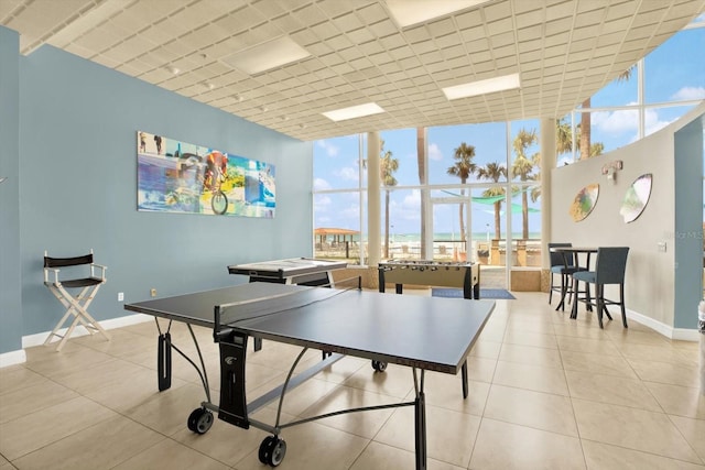 playroom with tile patterned floors, expansive windows, a towering ceiling, and baseboards