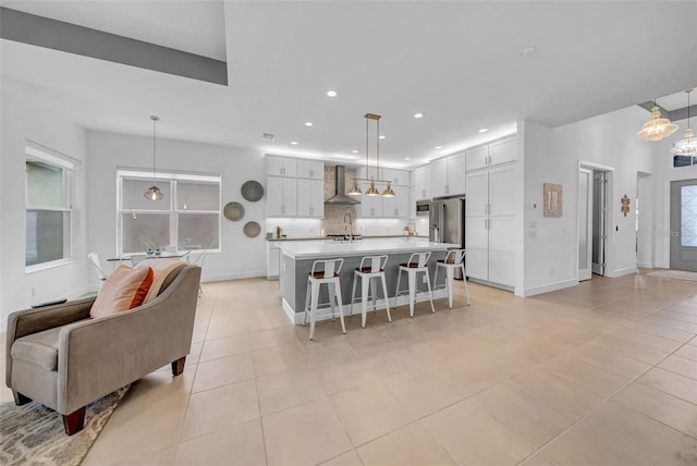 3096 Great Banyan Way, Wesley Chapel, FL 33543 - kitchen featuring wall chimney exhaust hood, light tile patterned floors, backsplash, a breakfast bar area, and light countertops