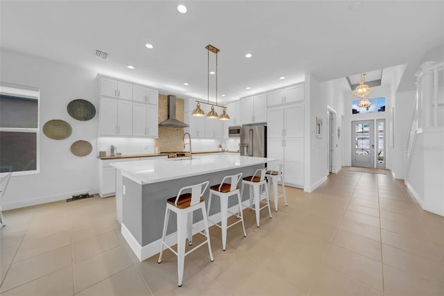3096 Great Banyan Way, Wesley Chapel, FL 33543 - kitchen featuring wall chimney exhaust hood, appliances with stainless steel finishes, backsplash, an island with sink, and a breakfast bar