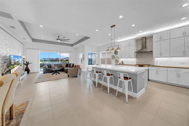 3096 Great Banyan Way, Wesley Chapel, FL 33543 - kitchen with wall chimney range hood, ceiling fan, backsplash, a sink, and open floor plan