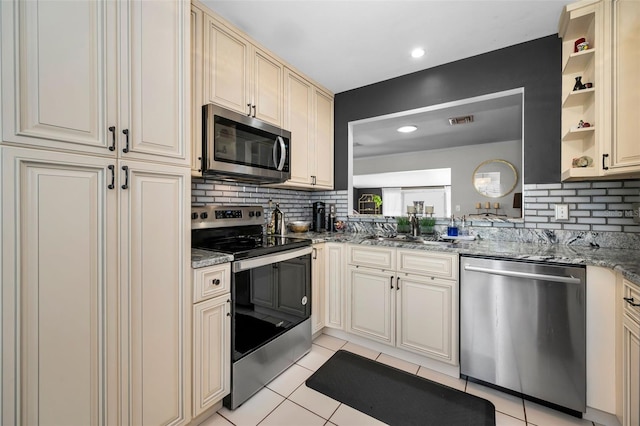 202 S Hesperides St, Tampa, FL 33609 - kitchen with stainless steel appliances, cream cabinets, tasteful backsplash, light tile patterned floors, and light stone counters