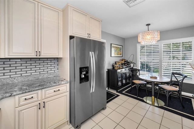 202 S Hesperides St, Tampa, FL 33609 - kitchen with stainless steel fridge, decorative backsplash, cream cabinets, light tile patterned flooring, and a chandelier