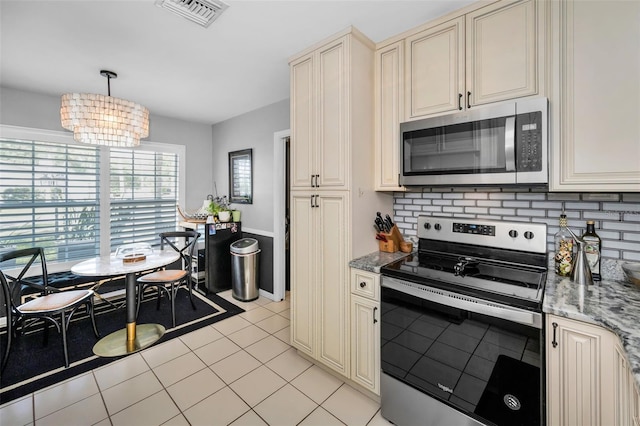 202 S Hesperides St, Tampa, FL 33609 - kitchen with stainless steel appliances, cream cabinetry, a chandelier, and light stone countertops