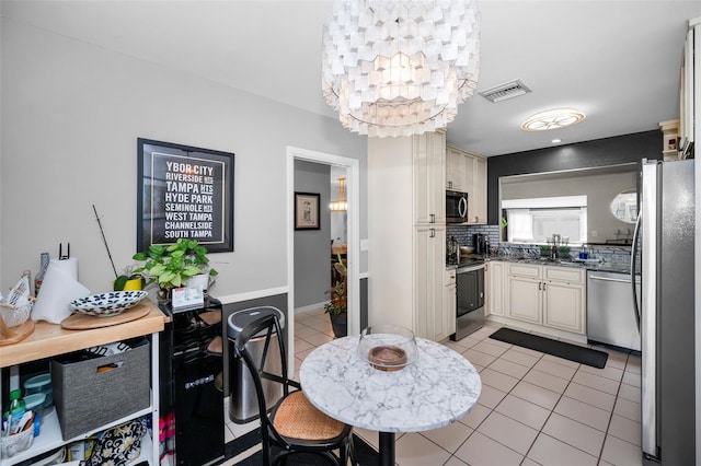 202 S Hesperides St, Tampa, FL 33609 - kitchen featuring appliances with stainless steel finishes, light tile patterned floors, decorative backsplash, and a chandelier
