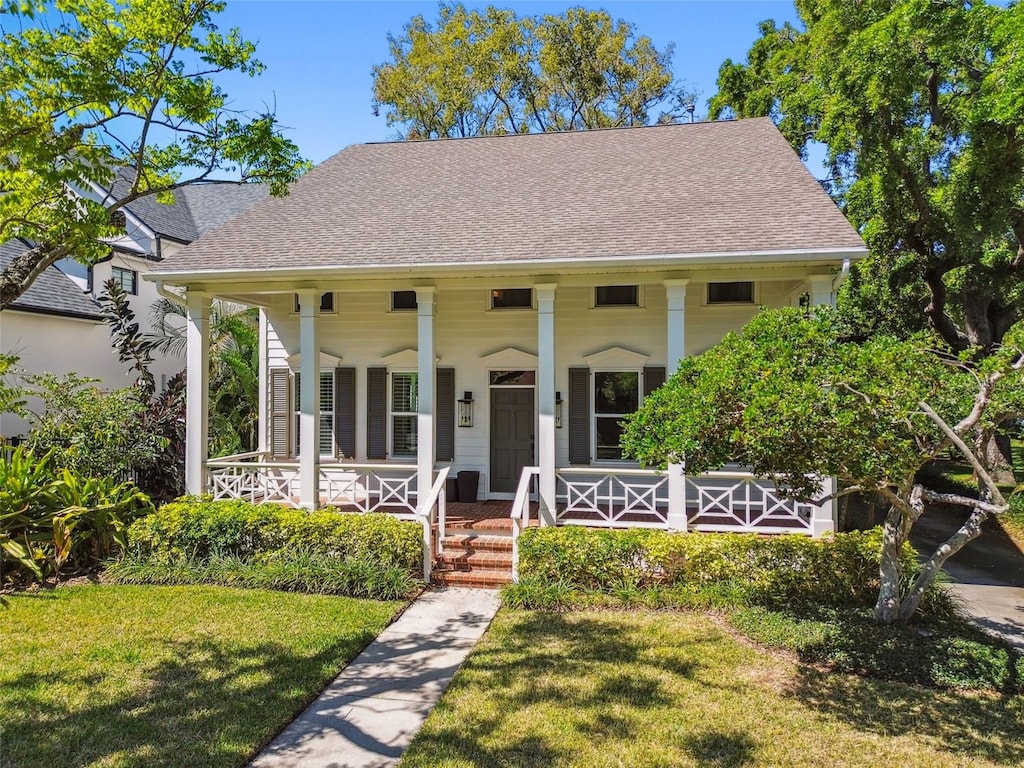 817 S Woodlyn Dr, Tampa, FL 33609 - view of front facade featuring a front lawn, a shingled roof, and covered porch
