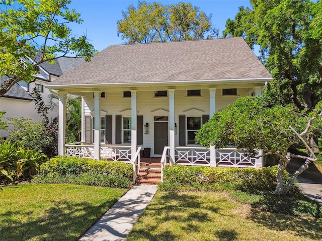 817 S Woodlyn Dr, Tampa, FL 33609 - view of front facade featuring a front lawn, a shingled roof, and covered porch