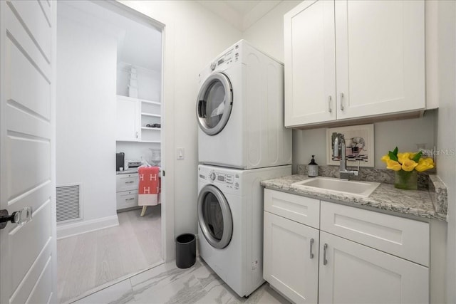 2501 S Dundee St, Tampa, FL 33629 - clothes washing area featuring stacked washer and clothes dryer, cabinet space, and light marble finish floors