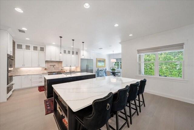 2501 S Dundee St, Tampa, FL 33629 - kitchen with an island with sink, stainless steel appliances, a sink, tasteful backsplash, and light wood finished floors