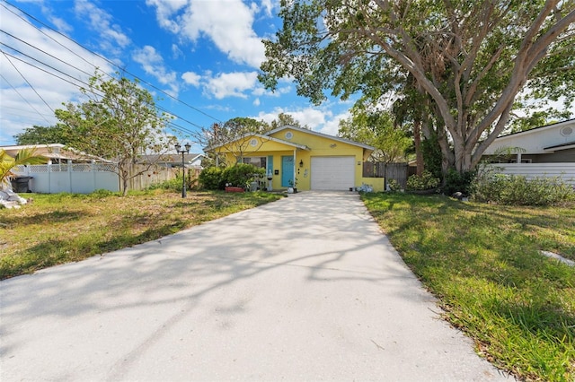view of front of property featuring an attached garage, fence, a front lawn, and concrete driveway