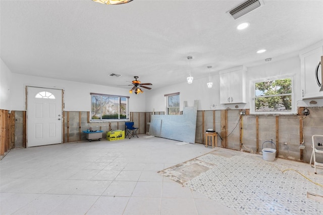 interior space with visible vents, a textured ceiling, and wainscoting