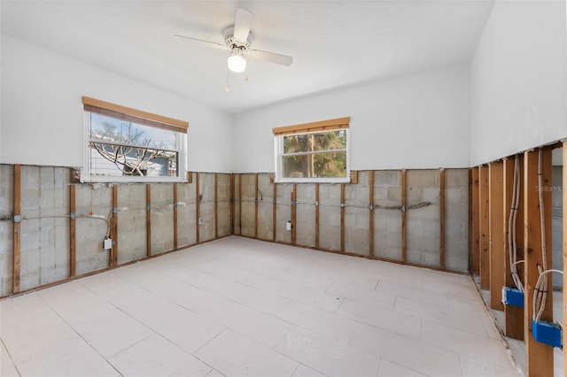 spare room featuring ceiling fan and a wainscoted wall