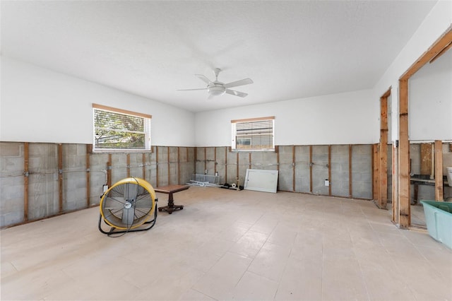 miscellaneous room featuring a healthy amount of sunlight, a wainscoted wall, and ceiling fan