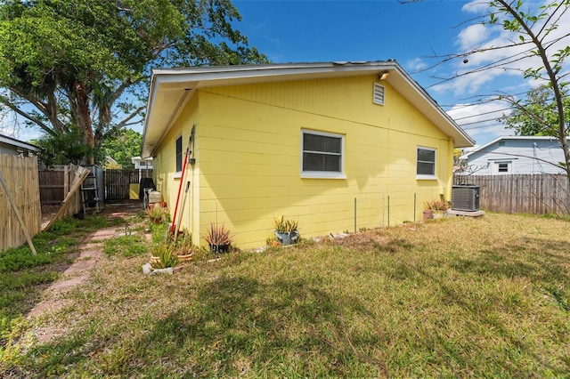 back of house with central AC, a fenced backyard, and a lawn