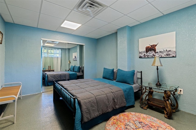 bedroom featuring visible vents, a paneled ceiling, and a textured wall