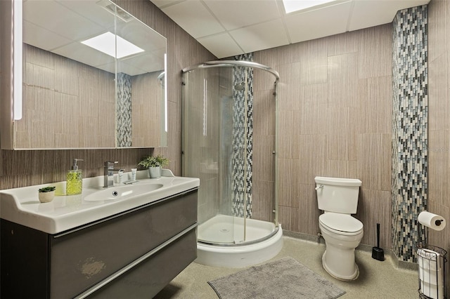 bathroom with a shower stall, vanity, a paneled ceiling, and toilet