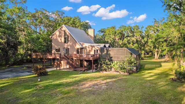 back of property featuring a deck, a lawn, a chimney, stairs, and a lanai