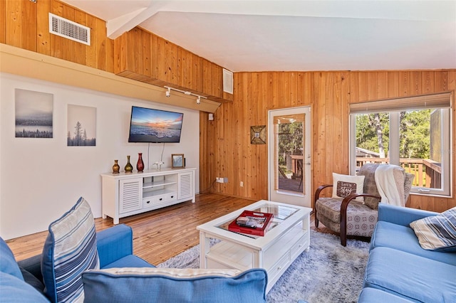 living area featuring visible vents, wood finished floors, and wood walls