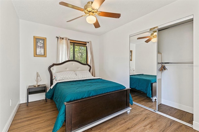 bedroom featuring wood finished floors, ceiling fan, baseboards, and a closet