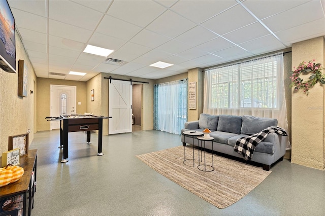 living room with visible vents, a wealth of natural light, a drop ceiling, and a barn door