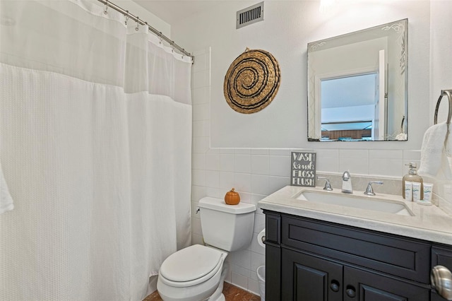 full bath featuring toilet, vanity, visible vents, and tile walls