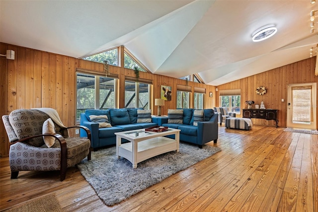 living room featuring wood walls, hardwood / wood-style flooring, a healthy amount of sunlight, and lofted ceiling
