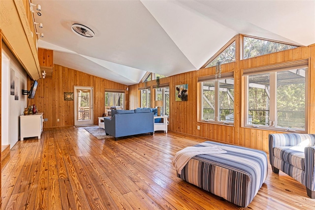 bedroom with wood walls, wood-type flooring, and vaulted ceiling