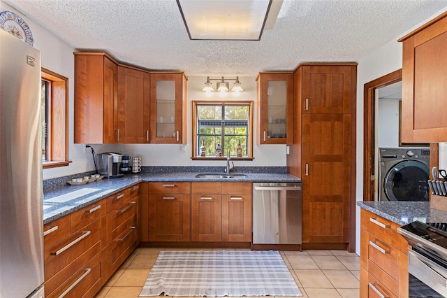 kitchen featuring a sink, a textured ceiling, washer / dryer, and stainless steel appliances