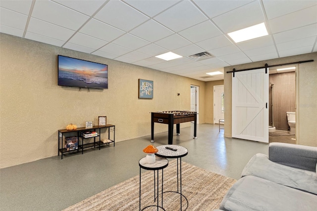 interior space featuring a textured wall, a barn door, a paneled ceiling, and visible vents