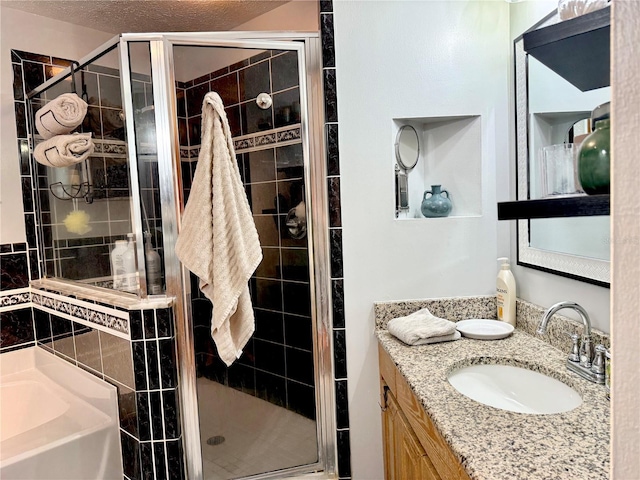 full bathroom featuring a stall shower, a garden tub, vanity, and a textured ceiling