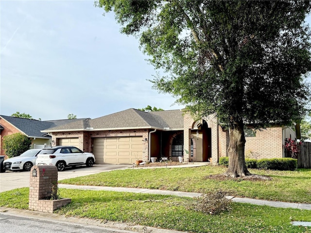 view of front facade with a front yard, brick siding, an attached garage, a shingled roof, and driveway