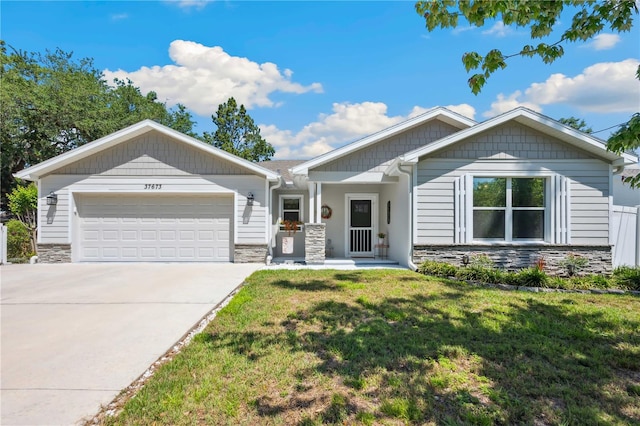 view of front of home featuring a front lawn, stone siding, a garage, and driveway